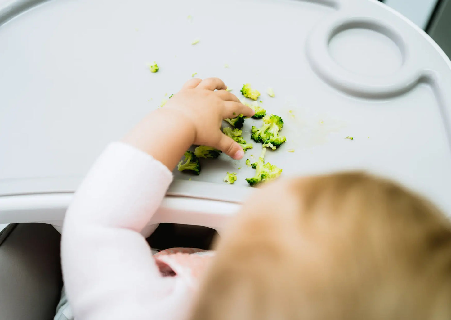 Baby feeding themselves pieces of fruit