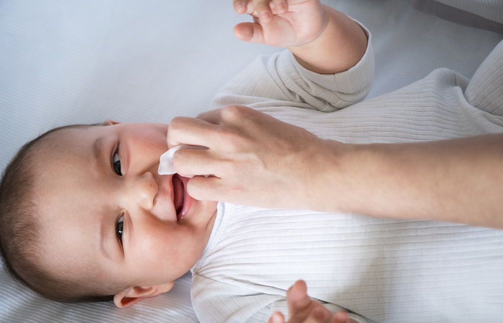 A parent cleaning a baby's nose with a nasal aspirator