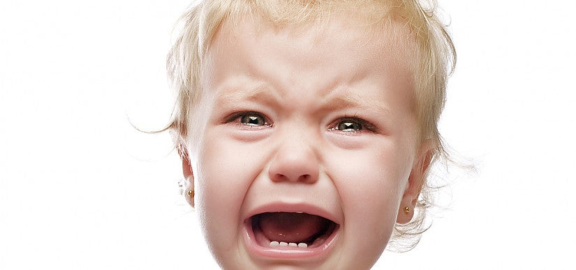 A parent comforting a crying baby in a sling