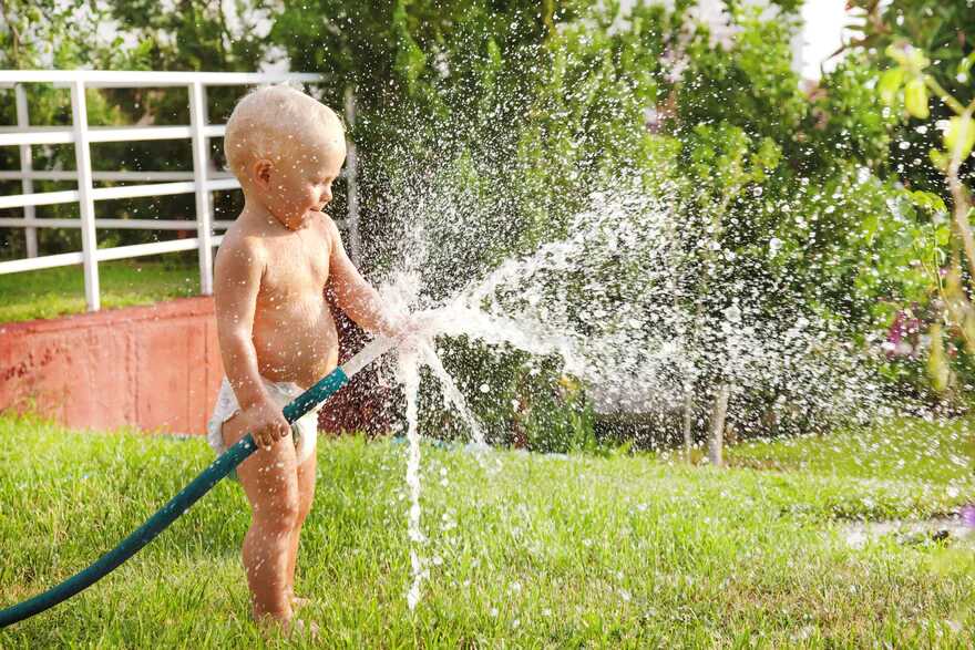A child playing with a garden hose